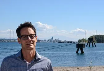 A man standing on the beach near water.