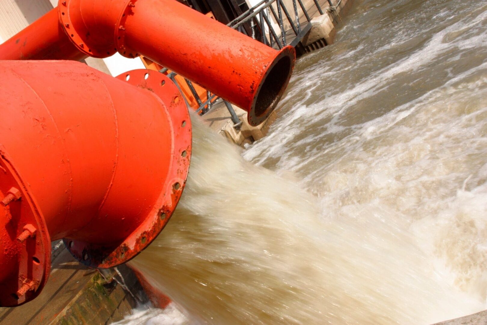 A red pipe is in the water near some waves.